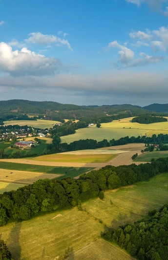 Panorama des Teutoburger Waldes mit weiten Feldern, sanften Hügeln und bewaldeten Abschnitten.
