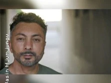 Porträt eines Mannes mittleren Alters mit bart und kurzgeschnittenem Haar, im Hintergrund unscharf.