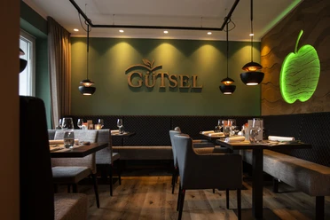 Innenansicht im Restaurant Gütsel Gemütliches Restaurant Gütsel mit stilvoller Beleuchtung, modernem Interieur und Apfel-Wanddekor.