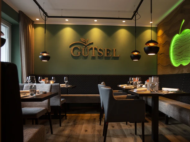 Innenansicht im Restaurant Gütsel Gemütliches Restaurant Gütsel mit stilvoller Beleuchtung, modernem Interieur und Apfel-Wanddekor.