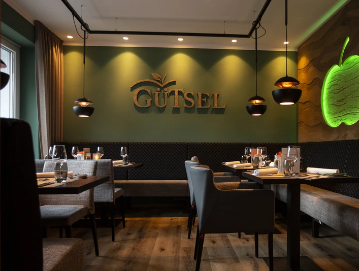 Innenansicht im Restaurant Gütsel Gemütliches Restaurant Gütsel mit stilvoller Beleuchtung, modernem Interieur und Apfel-Wanddekor.