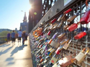 Hohenzollernbrücke Das Bild zeigt zahlreiche bunte Liebesschlösser, die eng an einem metallenen Gitter hängen, mit der Kathedrale Kölns im Hintergrund bei Sonnenschein.The picture shows numerous colorful love locks hanging closely on a metal lattice, with Cologne Cathedral in the background in the sunshine.
