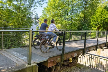 Die Waggongbrücke in Heiligenhaus Zwei Personen mit Helmen überqueren die Waggonbrücke in Heiligenhaus mit ihren Fahrrädern.