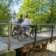 Die Waggongbrücke in Heiligenhaus Zwei Personen mit Helmen überqueren die Waggonbrücke in Heiligenhaus mit ihren Fahrrädern.