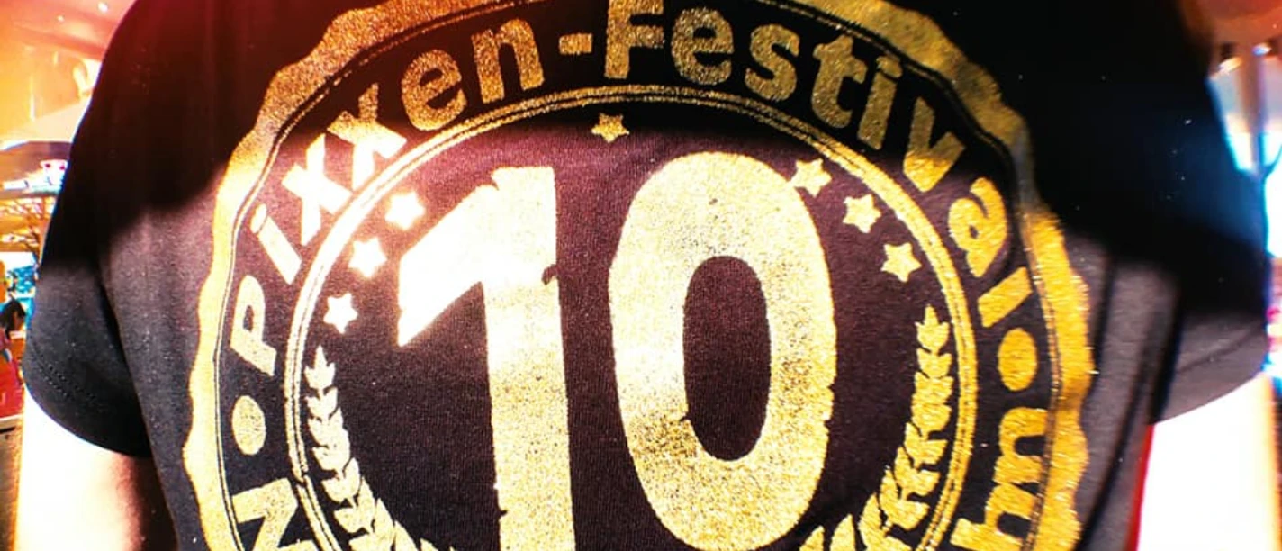 Pixxen.jpg Person mit T-Shirt zeigt das "Pixxen-Festival Neukamperfehn" Logo zum 10-jÀhrigen JubilÀum.