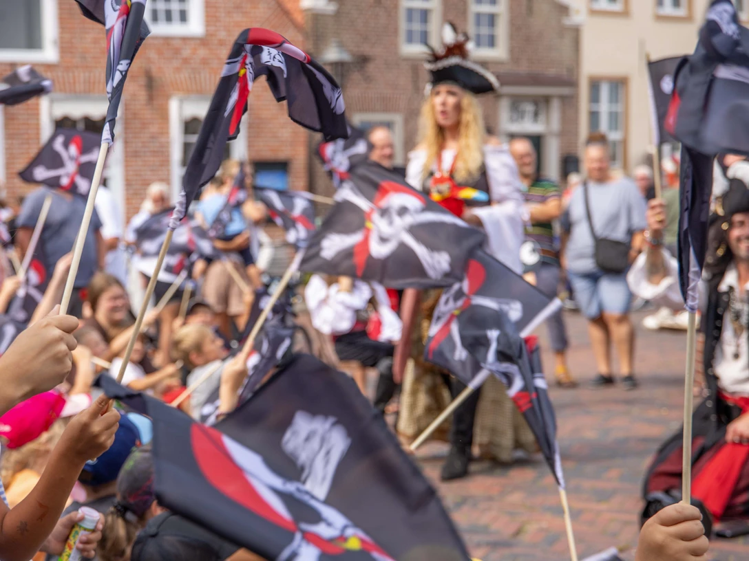 Greetsieler Piratenzauber Kinder schwenken Piratenflaggen bei einem fröhlichen Fest in Greetsiel mit verkleideten Piraten.