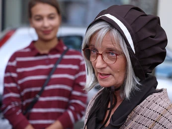 VIP_Fuehrung (7).JPG Zwei Frauen in historischen Kostümen stehen im Freien, eine spricht mit einem ernsten Ausdruck.