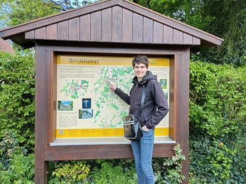 IMG_20240416_180536_HDR.jpg Ein junger Mann, der vor einer großen Infotafel in Bockhorst im Freien lächelt und posiert.