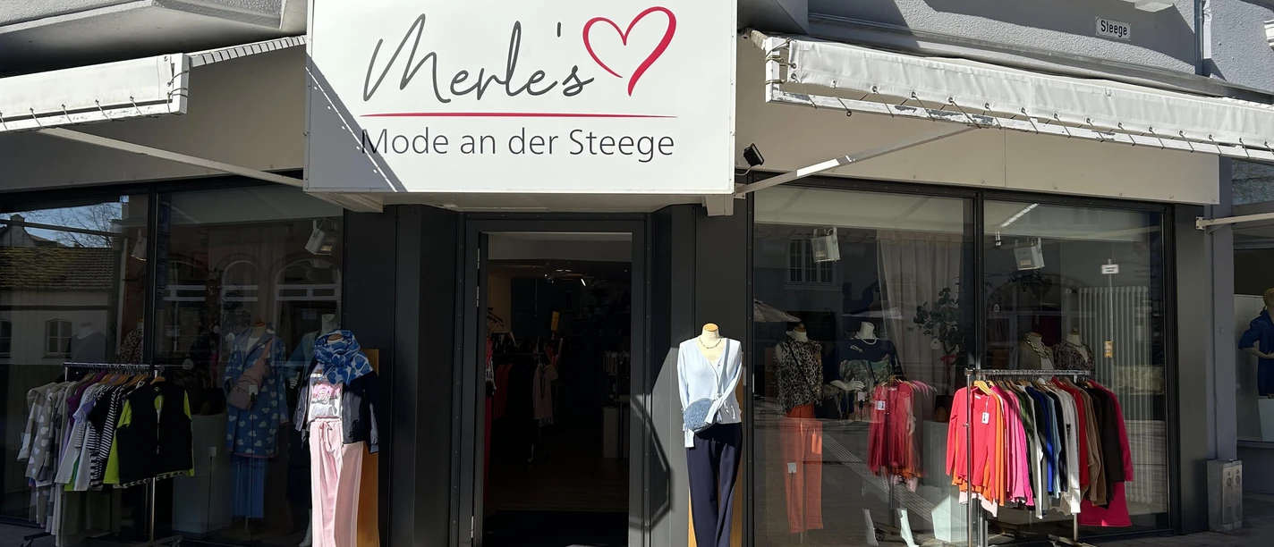 Schaufenster von Merle's Mode mit Kleidung, Schaufensterpuppen und großem Ladenschild
