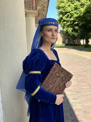 LAK: Almuth Cirksena Frau in königsblauem Mittelalterkleid mit Buch steht vor historischem Gebäude in Greetsiel.