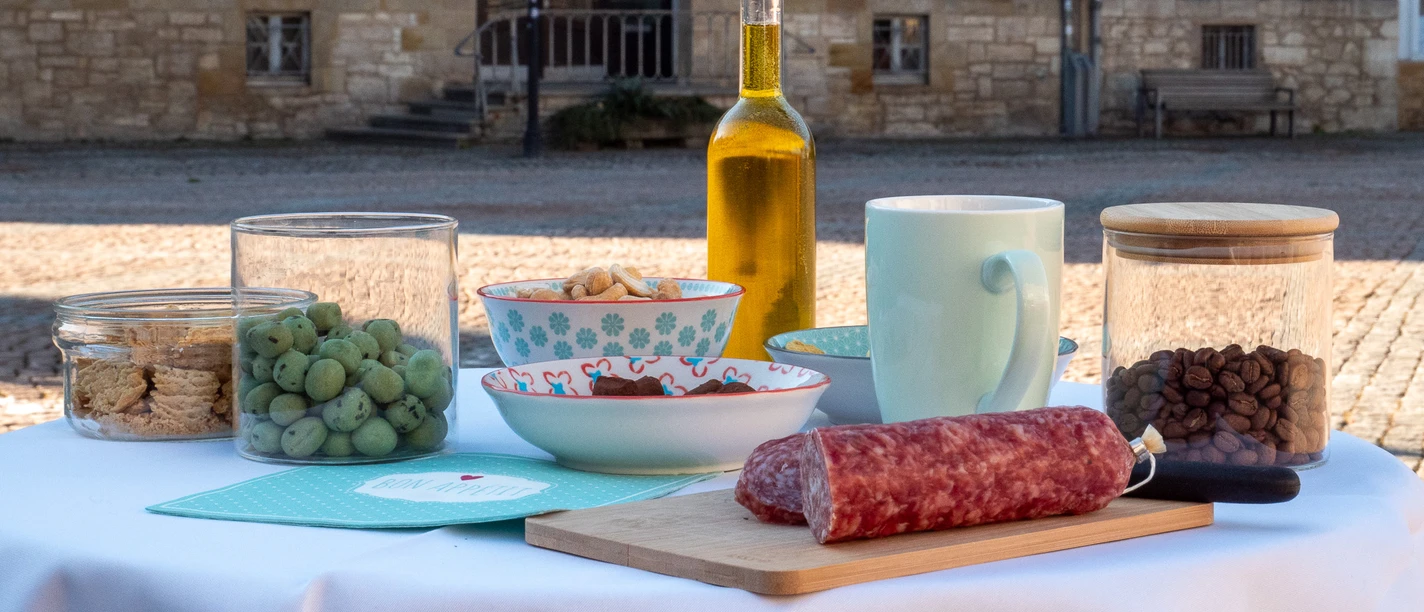 Genusspfade Gedeckter Tisch mit Leckereien zum Probieren auf dem sonnigen Stadtmarkt.