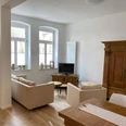 Wohn- Essbereich Bild 2.JPG Heller Wohn- und Essbereich mit beige Sofas, Holzschrank, Esstisch und großen Fenstern.