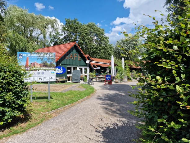 Wohnmobilstellplatz_Rhauderfehn_Ostfriesland Ein kleines Café-Gebäude mit Sitzgelegenheiten vor dem Gebäude.