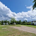 Wohnmobilstellplatz_Rhauderfehn_Ostfriesland Grüne Wiese mit geparkten Wohnmobilen unter einem weiten Himmel mit weißen Wolken.