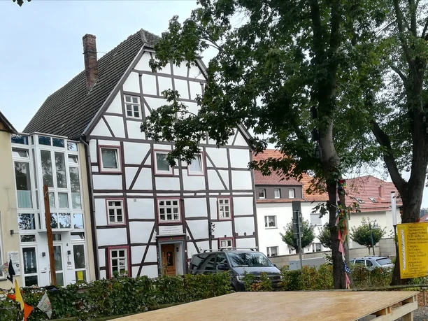 IMG-20221216-WA0002.jpg Fachwerkhäuser stehen nebeneinander, umgeben von Bäumen und parkenden Autos, in einer deutschen Stadt.