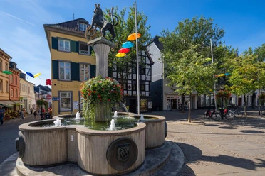 Löwenbrunnen auf dem Marktplatz in Ratingen Löwenbrunnen auf Ratingens Marktplatz mit Springbrunnen, Säule und Löwenstatue im lichtdurchfluteten Umfeld.