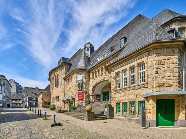Historisches Bürgerhaus in Velbert-Langenberg Historisches Gebäude aus Sandstein mit markantem Schieferdach und grünen Türen in Velbert-Langenberg.