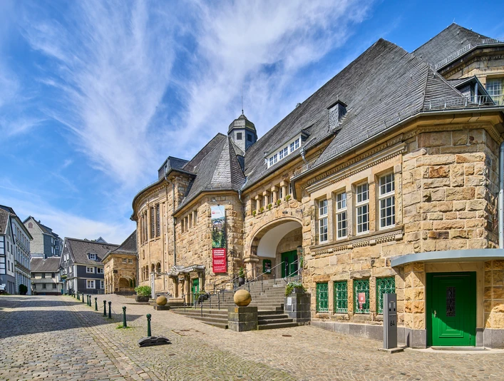 Historisches Bürgerhaus in Velbert-Langenberg Historisches Gebäude aus Sandstein mit markantem Schieferdach und grünen Türen in Velbert-Langenberg.