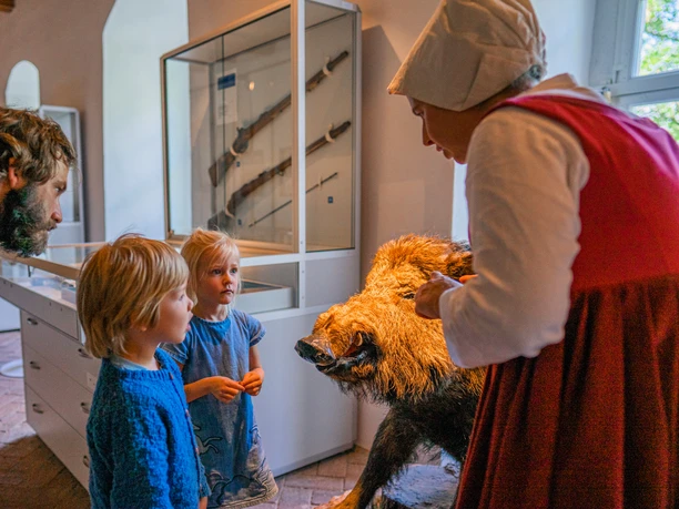 Lors de la visite guidée du château de Gnandstein, la femme de chambre déguisée raconte aux enfants dans la salle d'exposition des histoires et des connaissances sur le château, famille, loisirs, enfants, excursion