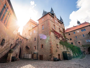 Innenhof der Burg Kriebstein - Sehenswürdigkeiten in der Leipzig Region Der Innenhof der Burg Kriebstein mit Ranken an den Fassaden und Treppenaufgang unter dem Sonnenschein, Ausflug, Freizeit, Geschichte, Burgenland