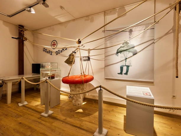 Heringsfängermuseum Ausstellungsraum im Heringsfängermuseum mit Rettungsring, Infotafel, Seilen und historischem Bild.