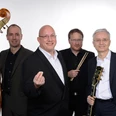 Jörg Hegemann Trio & Rolf Marx Vier Musiker in formeller Kleidung lächeln, mit Klavier, Gitarre, Kontrabass und Schlagzeug.