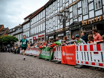 Bierstadtlauf 2024 Lots of people and a runner in front of a large half-timbered house.