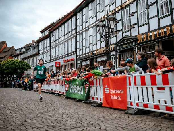 Bierstadtlauf 2024 Lots of people and a runner in front of a large half-timbered house.