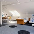 Poettner2.jpg Helle, geräumige Dachwohnung mit modernen Möbeln, zwei Sofas und Esstisch unter Dachfenstern.