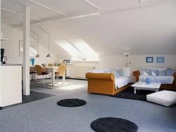 Poettner2.jpg Helle, geräumige Dachwohnung mit modernen Möbeln, zwei Sofas und Esstisch unter Dachfenstern.