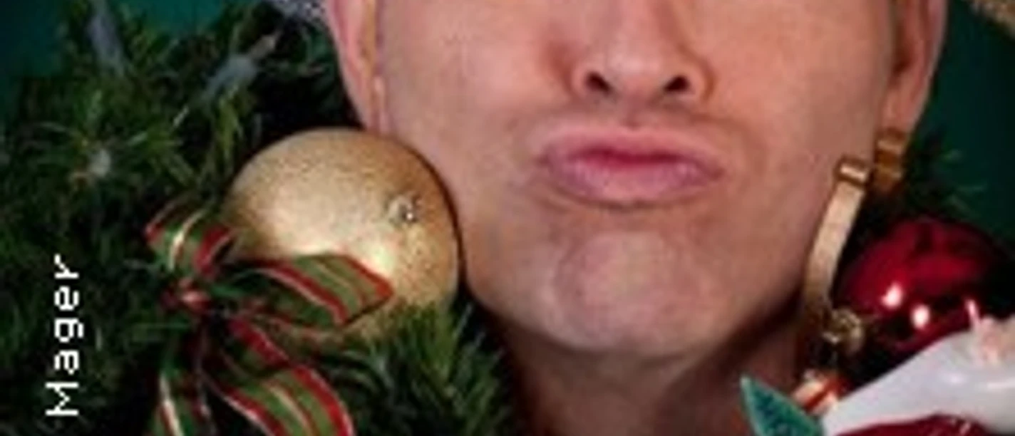 Ein Mann mit Weihnachtskranz um den Hals macht einen Kussmund und trägt einen weißen Hut.