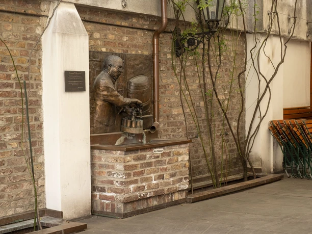 Lommerzheim Bronzerelief von Hans Lommerzheim mit Fass und Zapfhahn an einer Backsteinwand im Innenhof.