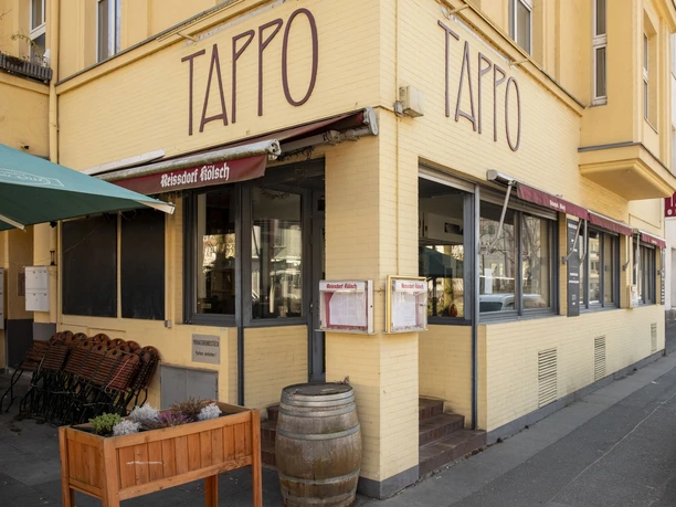 Tappo Gemütliches Restaurant „Tappo“ mit gelber Fassade und großen Fenstern an einer Straßenecke.
