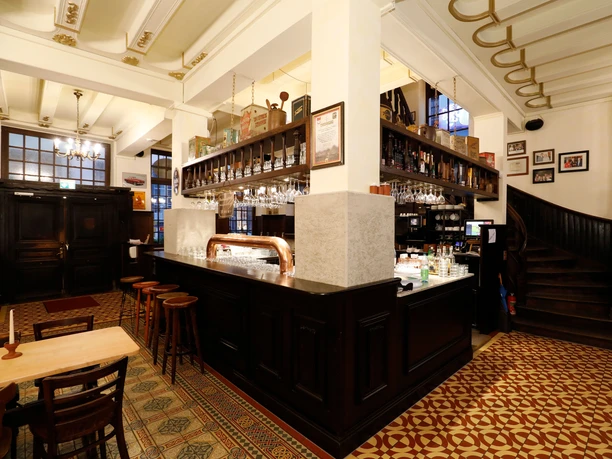 Haxenhaus Counter of a traditional brewery with wooden bar stools and decorative tiled floor.