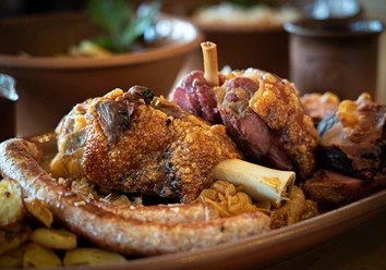 Haxenhaus Knusprige Schweinshaxe und Bratwurst auf einem rustikalen Holzteller mit Sauerkraut serviert.