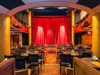 Varietésaal im Krystallpalast Varieté Leipzig - Abendveranstaltungen in Leipzig Blick auf die Bühne mit rotem Vorhang im Varietésaal des Krystallpalast Varieté Leipzig mit zahlreichen Stühlen und Tischen bei heller Beleuchtung, Kultur, AbendveranstaltungView of the stage with red curtain in the Varietésaal of the Krystallpalast Varieté Leipzig with numerous chairs and tables under bright lighting, Culture, Evening eventPohled na jeviště s červenou oponou ve Varietésaalu Krystallpalast Varieté Leipzig s mnoha židlemi a stoly pod jasným osvětlením, Kultura, Večerní akceWidok na scenę z czerwoną kurtyną w Varietésaal w Krystallpalast Varieté Leipzig z licznymi krzesłami i stołami przy jasnym oświetleniu, Kultura, Impreza wieczornaUitzicht op het podium met rood gordijn in de Varietésaal van het Krystallpalast Varieté Leipzig met talrijke stoelen en tafels onder felle verlichting, Cultuur, AvondevenementVista del palcoscenico con sipario rosso nel Varietésaal del Krystallpalast Varieté di Lipsia con numerose sedie e tavoli sotto una luce intensa, Cultura, Evento serale