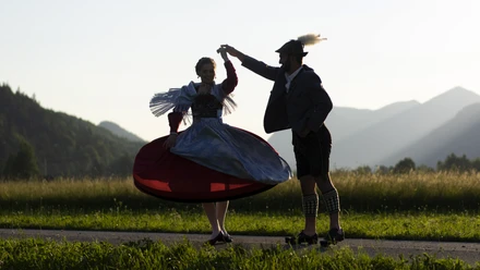 Trachtenpaar im ZugspitzLand Trachtenpaar tanzend bei Sonnenuntergang vor Bergkulisse