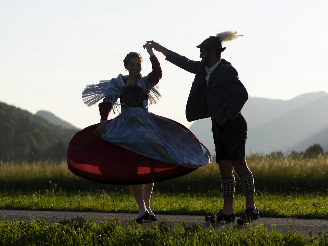 Trachtenpaar im ZugspitzLand Trachtenpaar tanzend bei Sonnenuntergang vor Bergkulisse