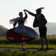 Trachtenpaar im ZugspitzLand Trachtenpaar tanzend bei Sonnenuntergang vor Bergkulisse
