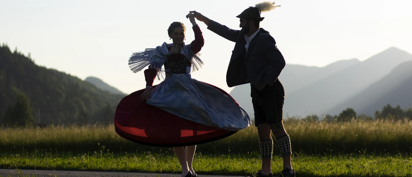 Trachtenpaar im ZugspitzLand Trachtenpaar tanzend bei Sonnenuntergang vor Bergkulisse