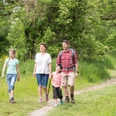 Wandern mit der Familie auf dem neanderland STEIG Familie wandert lächelnd zusammen auf einem schmalen Pfad inmitten grüner Natur im neanderland STEIG.