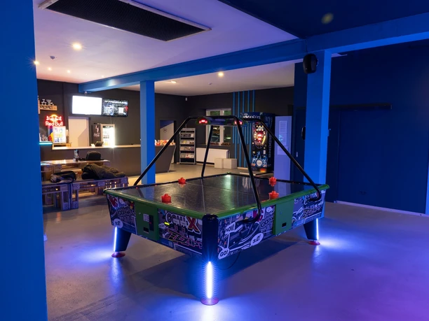 Arcade Ein modern gestalteter Spielraum mit einem beleuchteten Airhockey-Tisch im Fokus.