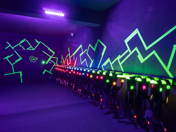 Westenraum Ein dunkler Raum mit leuchtenden Neonlichtern und Lazer-Equipment an der Wand.