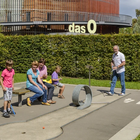 Family playing minigolf, In the background the multifunctional hall "das O", Leisure, Zoo, Family outing