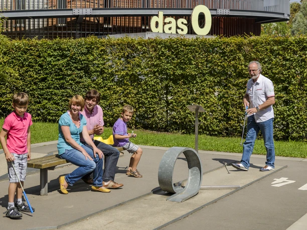 Family playing minigolf, In the background the multifunctional hall "das O", Leisure, Zoo, Family outing