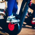 Fitness Gezeitenland (2).jpg Auf dem Bild sind die Beine einer Person auf einem Fitness-Fahrrad zu sehen, fokussiert auf die Pedale.