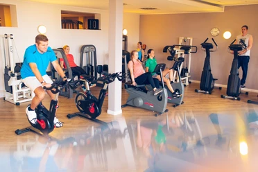 Fitness room at Gezeitenland Borkum with modern training equipment and athletes doing fitness activities.