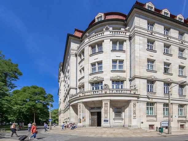 Pohled na budovu s kulatým rohem, v jejímž "kulatém rohu" se nachází stejnojmenné muzeum, v pozadí jasně modrá obloha, památník, historie