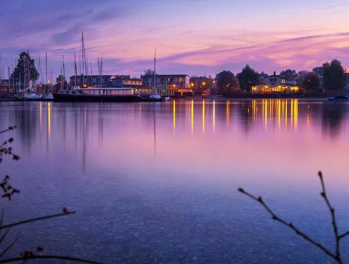 Cospudener See mit Sauna im See - Wellness in Leipzig und Region Der rosa und lila gefärbte Himmel spiegelt sich im Cospudener See, Am Pier liegen einige Segelboote an und die Sauna im See ist hell erleuchtet, Erholung, Wellness, Ausflug, Leizpiger Neuseenland