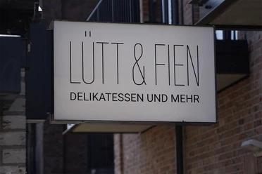 buesum-Lu╠êtt&Fien Schmecken_15.05.25-2560x1707.png Schild an der Wand wo Lütt & Fien Delikatessen und Mehr drauf steht ´.